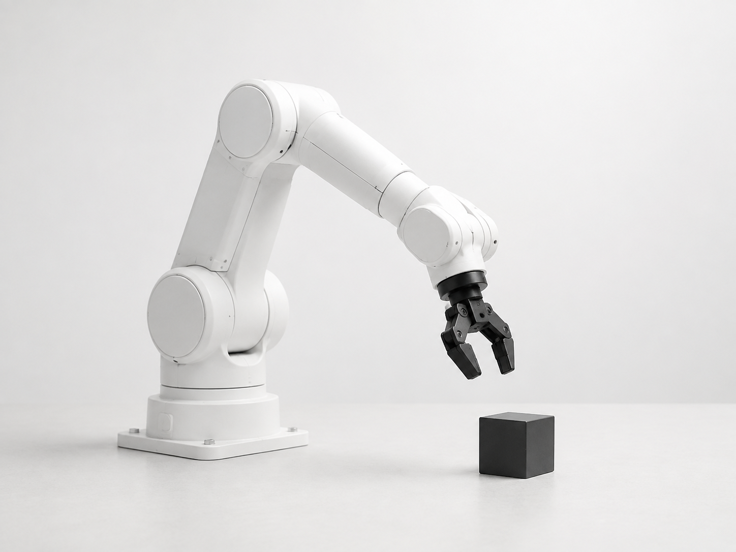 Illustrative white robotic arm reaching toward a cube in a controlled lab